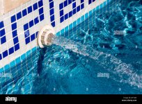 vista-detallada-de-un-chorro-de-agua-entrante-en-una-piscina-con-azulejos-azules-j3f1am.jpg